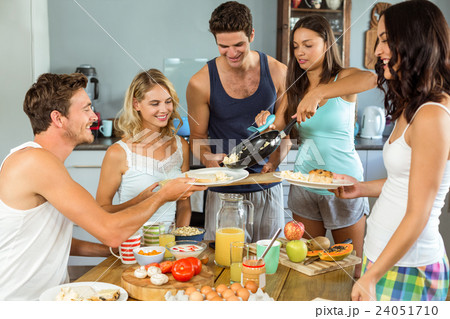 Couple serving breakfast to friends at table Couple serving breakfast to friends at table 24051710
