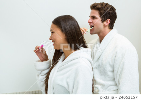 Couple in bathrobe brushing their teeth in bathroom Couple in bathrobe brushing their teeth in bathroom 24052157