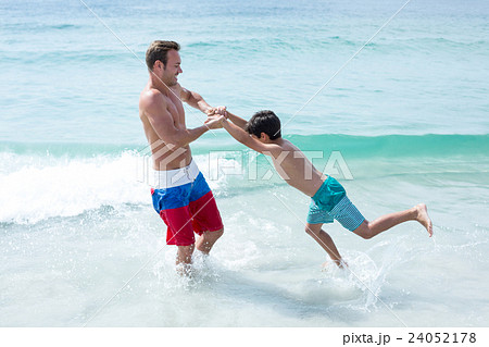 Father playing with son at beach  24052178