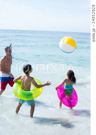 Father and children playing with ball on shore  24052929