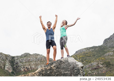 Excited young couple on rock against sky Excited young couple on rock against sky 24053436