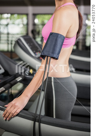 Mid section of woman exercising on treadmill with mobile on armband Mid section of woman exercising on treadmill with mobile on armband 24053770