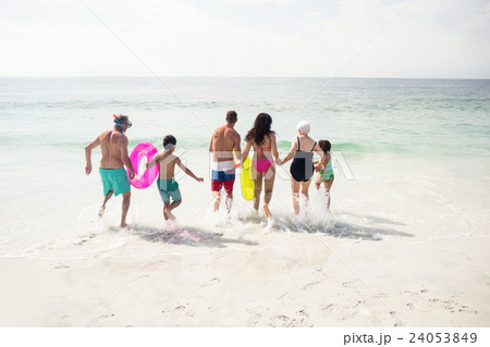 Rear view of family running towards sea Rear view of family running towards sea 24053849