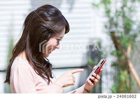 屋外で携帯電話で調べ物をする女性 検索 携帯をいじる スマートフォン スマホ 手元 パーツ Arの写真素材