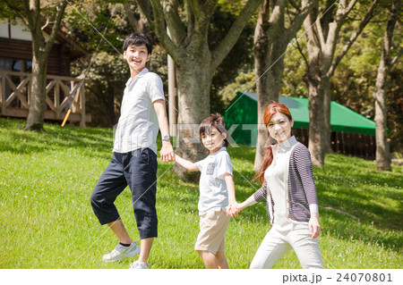公園を手を繋いで歩く家族 24070801