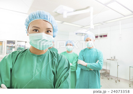 surgeon posing with a team in a surgical room 24073358