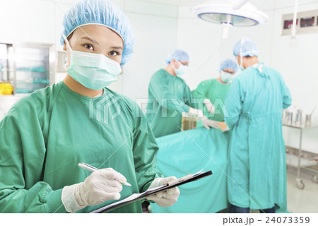Surgeons writing medical record in operation room 24073359