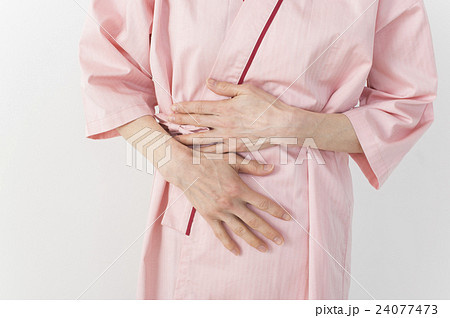検査着でお腹を押さえるミドル女性 24077473