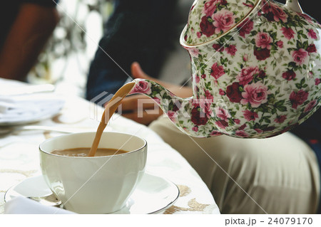 Tea pours from the pot painted with pink flowers 24079170