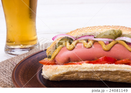 hot dog with a glass of beer on a white table 24081149
