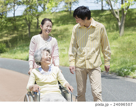車椅子に乗るシニア女性と日本人夫婦 24096507