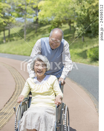 車椅子に乗る女性を押す男性 24096512
