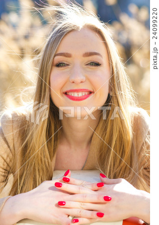 A portrait of smiling blonde standing outside  24099220