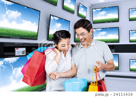 Composite image of older asian couple with shopping bags 24111419