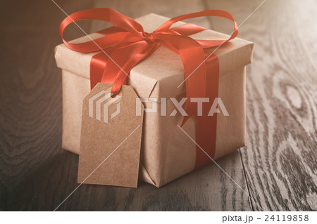 rustic present box with red ribbon on wood table rustic present box with red ribbon on wood table 24119858