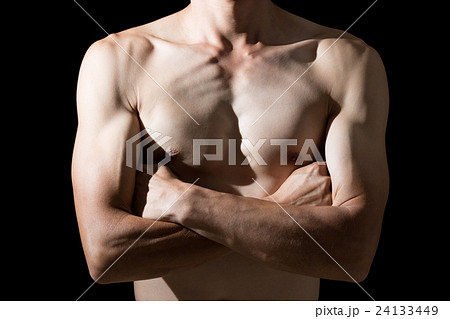 腕組みをする裸の男性 黒バックの写真素材