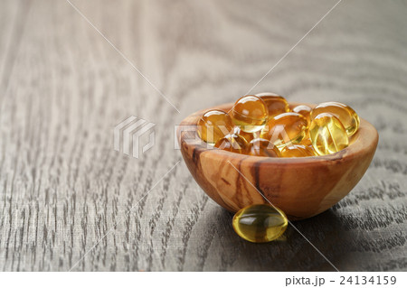 fish oil capsules in wooden bowl on table 24134159