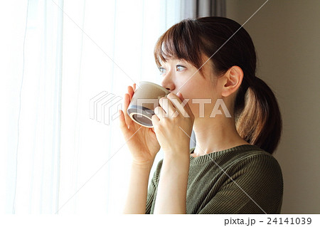 窓際でコーヒーを飲む女性女性の写真素材