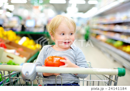Toddler sitting in the shopping cart in a supermarket Toddler sitting in the shopping cart in a supermarket 24141184