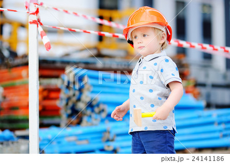 Little builder in hardhats with hammer working outdoors Little builder in hardhats with hammer working outdoors 24141186