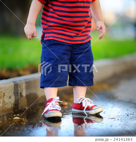 Toddler boy standing in a puddle 24141363