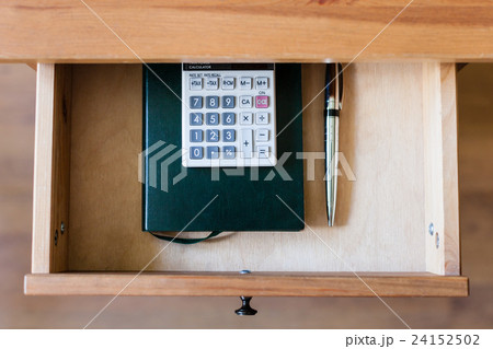 pen, calculator and notebook in open drawer 24152502