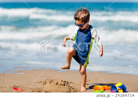 Cute boy demolishing sand castle Cute boy demolishing sand castle 24164714