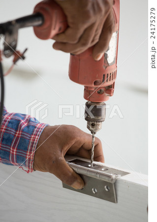 door installation. Worker drills a hole for bolt  24175279