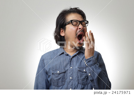 The asian man in blue denim shirt is feeling lazy. The asian man in blue denim shirt is feeling lazy. 24175971