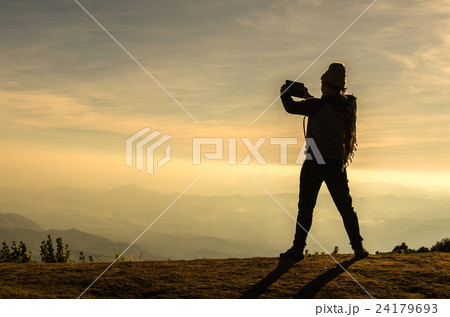 silhouette of a man with action take photo by tablet over the mountains landscape 24179693