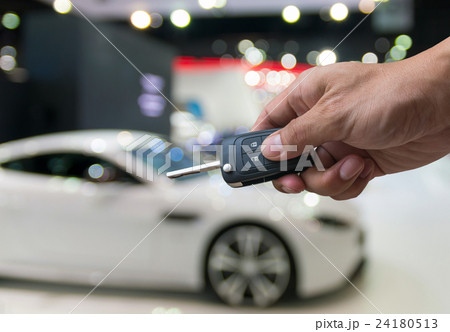 Man hand holding a car key remote on photo blurred of car, technology safety transportation concept 24180513