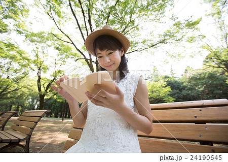 公園のベンチで本を読む女性 24190645