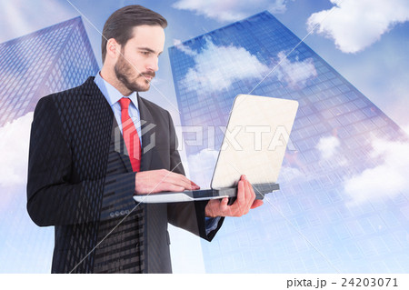 Composite image of focused businessman using his laptop 24203071