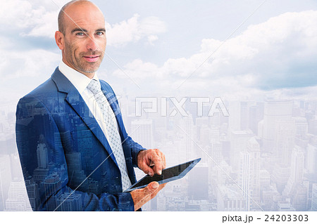 Composite image of businessman using a tablet and smiling at the Composite image of businessman using a tablet and smiling at the 24203303