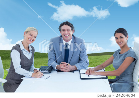 Composite image of portrait of smiling business people sitting at conference table 24204604