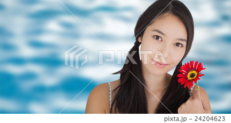 Composite image of smiling woman holding flower 24204623
