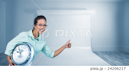 Composite image of delighted businesswoman holding a clock 24206217