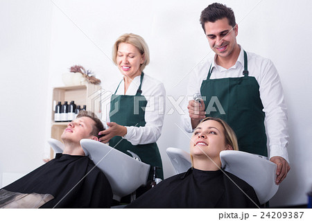Two hairdressers working with clients . Two hairdressers working with clients . 24209387