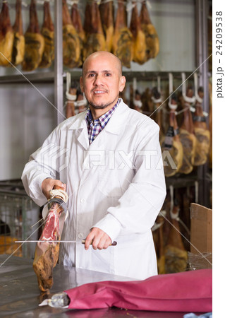 Mature butcher slicing jamon at store. 24209538