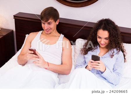 Couple with smartphones in bed. Couple with smartphones in bed. 24209665