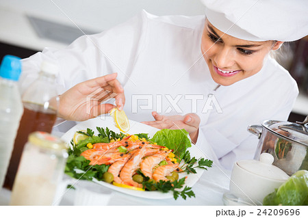 Professional female cook decorating prepared dish of shrimps Professional female cook decorating prepared dish of shrimps 24209696