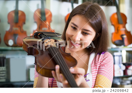 Girl choosing violin in music shop. Girl choosing violin in music shop. 24209842