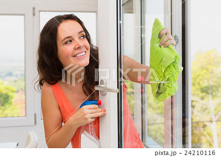 Long-haired woman washing windows with spray 24210116