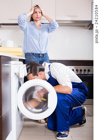 Repairman and woman near washing machine. 24210584