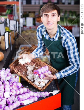 Portrait of male seller with stalks of garlic in grocery Portrait of male seller with stalks of garlic in grocery 24212570
