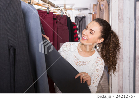 Happy female brunette choosing new trousers Happy female brunette choosing new trousers 24212757