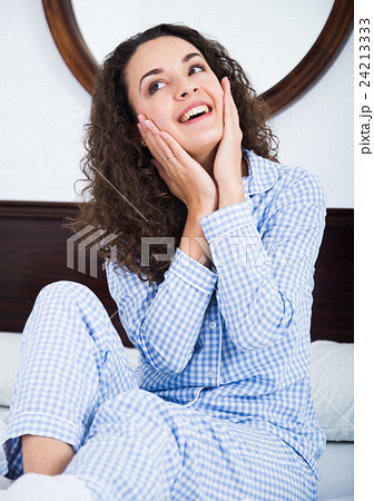 Young woman rubbing face with fingers and smiling Young woman rubbing face with fingers and smiling 24213333