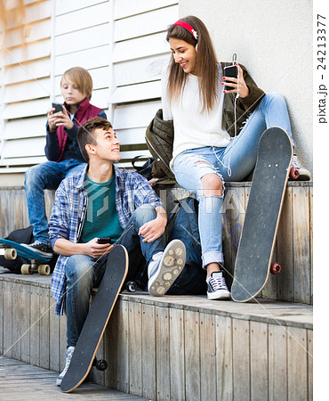 Three teenagers with phones outdoors . Three teenagers with phones outdoors . 24213377
