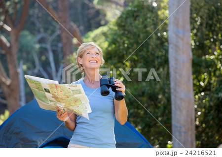 Mature woman smiling and holding binoculars and map Mature woman smiling and holding binoculars and map 24216521