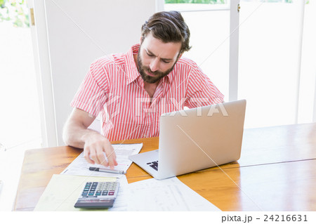 Young man calculating his bills Young man calculating his bills 24216631